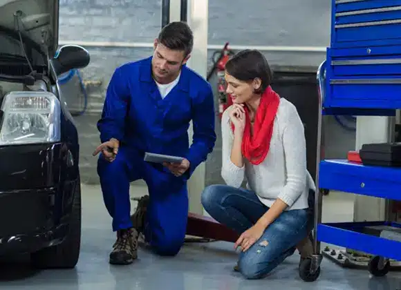 Auto body technician discussing vehicle repairs with a customer in a San Antonio auto repair shop, emphasizing customer service and satisfaction.